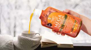 Tropical Oasis liquid vitamins being poured into a small cup next a wintry window.