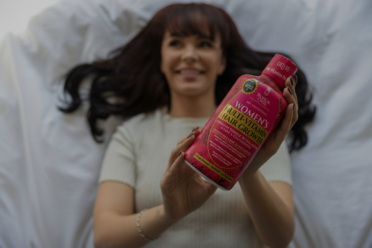 Woman holding two bottles of Women's Multi-Vitamin Hair Growth by Tropical Oaiss product against a white background